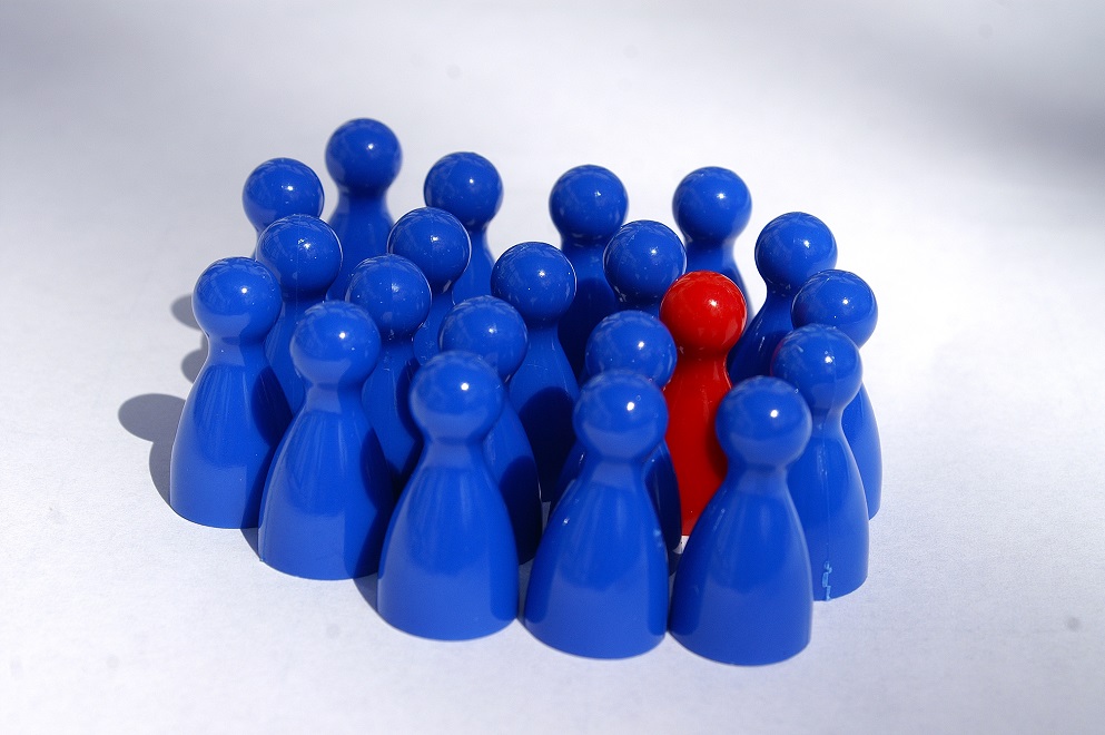 Bild mit einer gruppe von blauen Spielfiguren. In der Mitte steht eine rote Spielfigur.